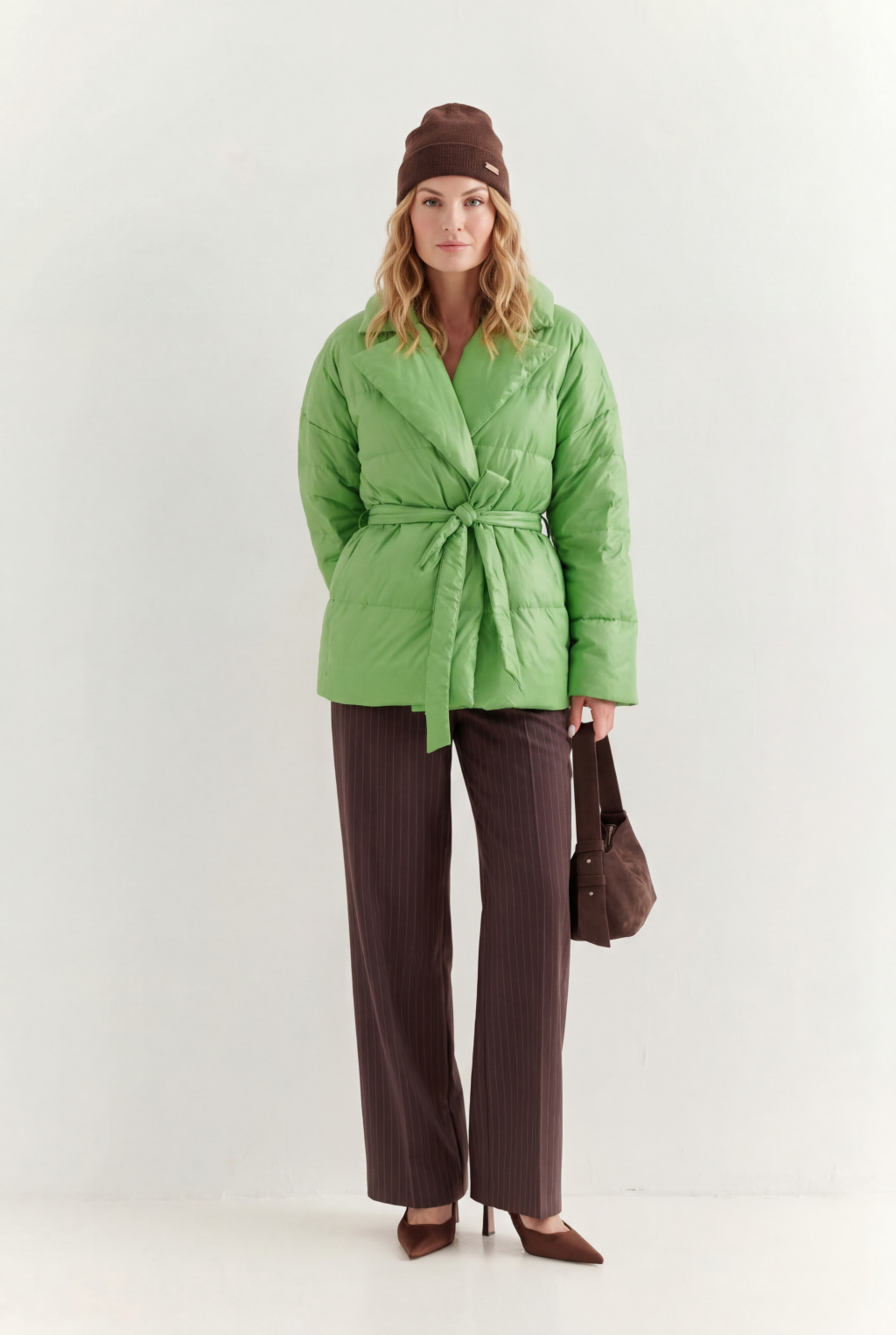 Короткий стеганый пуховик с английским воротником в цвете зеленой мяты, застегивается на кнопки, имеет регулируемый пояс, что позволяет носить изделие в разных вариациях.