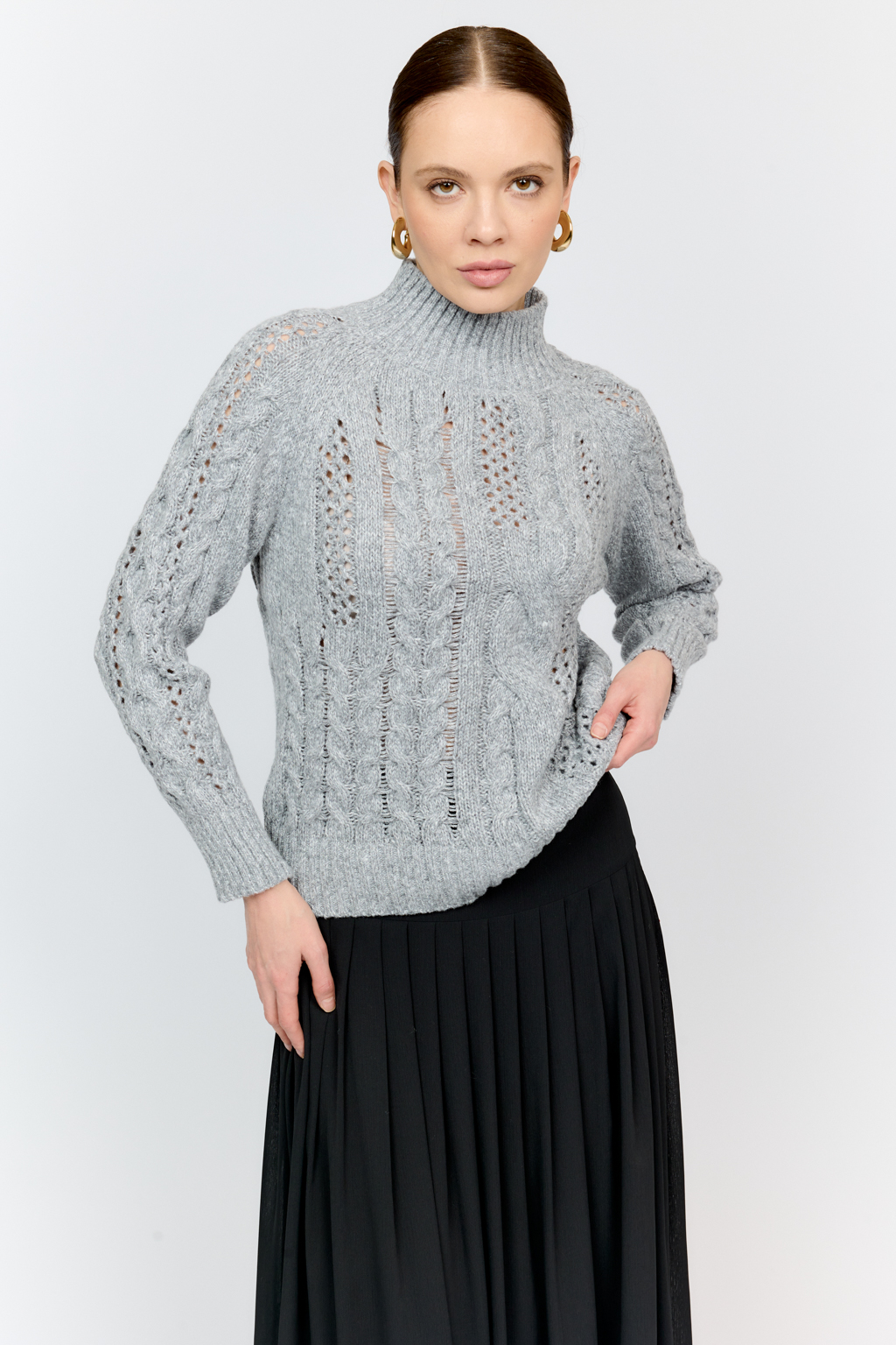 Свитер серого цвета из мягкой пряжи фигурной вязки с ассиметричными косами, с высокой горловиной и длинным рукавом реглан отлично стилизуется с денимом и обувью на плоском ходу.