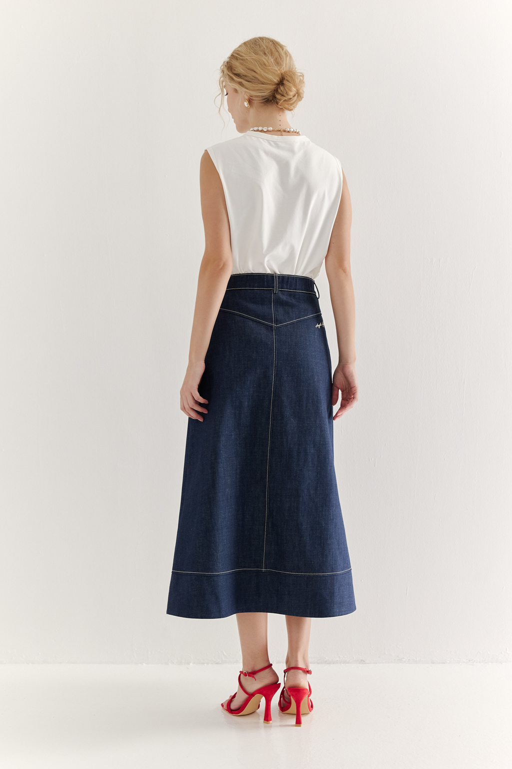 Топ-майка из хлопкового трикотажа молочного цвета в монохромном решении, горловина и проймы обработаны основным материалом.