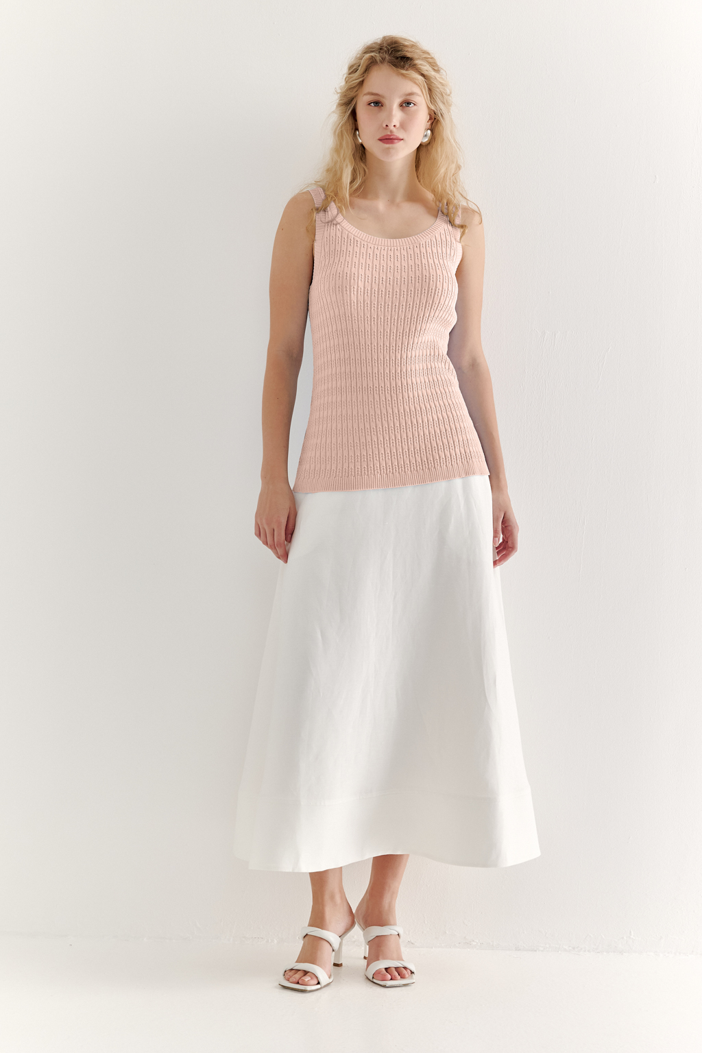 Фактурный топ-майка прилегающего силуэта из вискозной пряжи связана косами, проймы и горловина отделаны вязанными кантами. Цвет – розовая пудра.