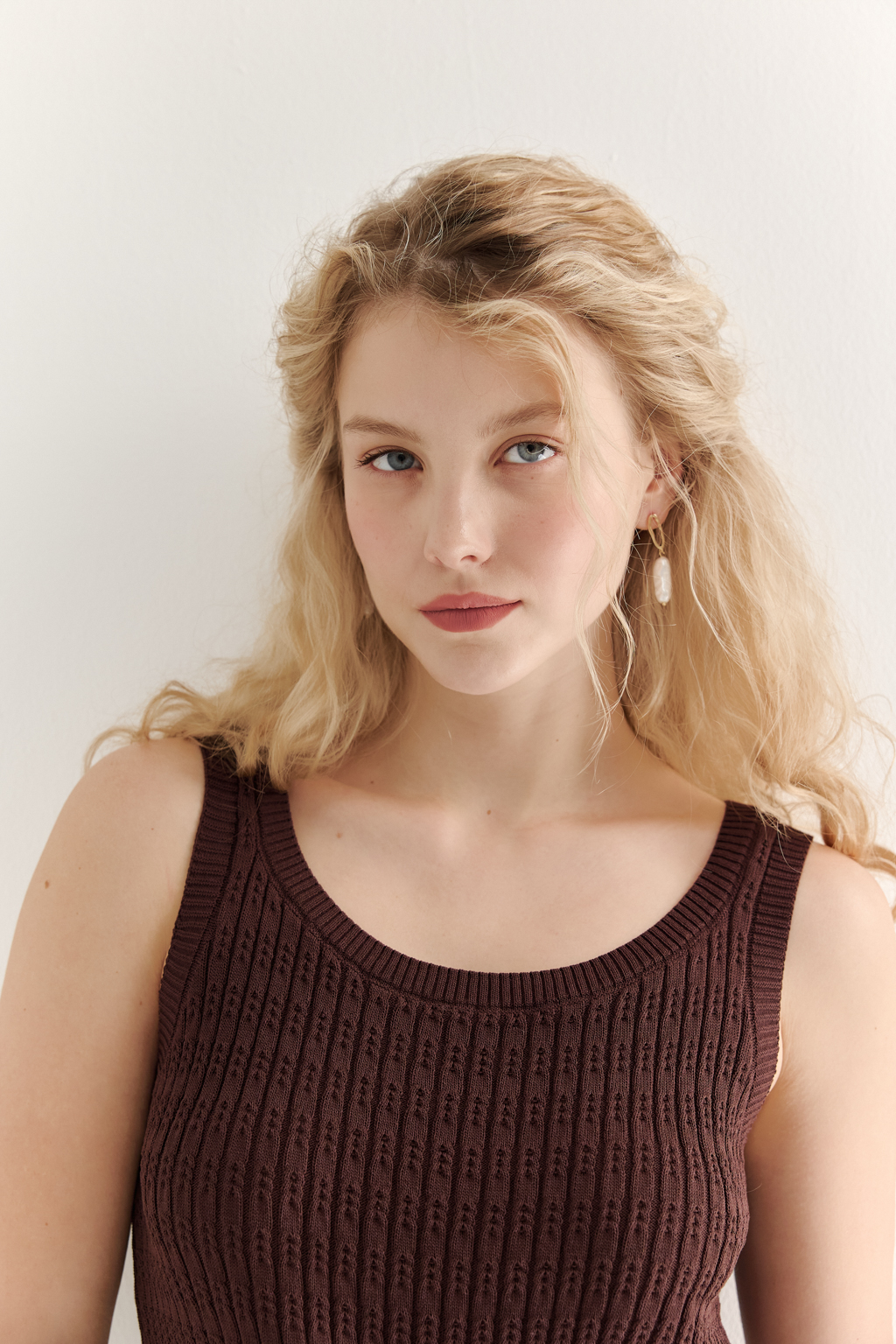 Фактурный топ-майка прилегающего силуэта из вискозной пряжи связана косами, проймы и горловина отделаны вязанными кантами. Цвет – шоколадно-коричневый.