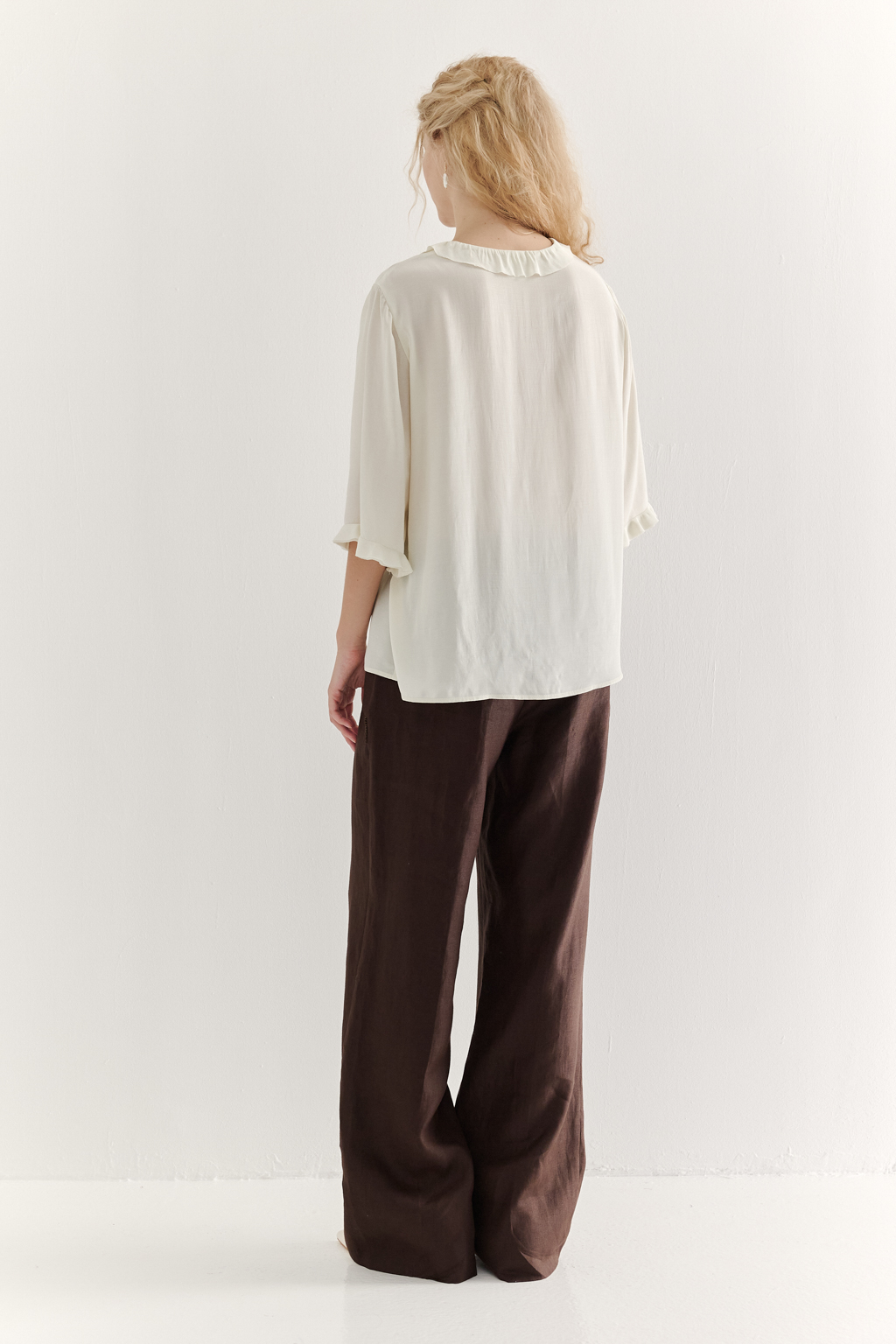 Эта романтичная блуза выполнена из вискозного крепа в нежном оттенке словочное масло. Горловина и рукава украшены изящными рюшами, добавляющими образу легкости и утонченности. Оригинальный разрез спереди кокетливо завязывается на тонкий шнур-рулик и фиксируется воздушной петлей на пуговицу. Прямой силуэт и рукава длиной одна вторая обеспечивают комфорт и свободу движений. Эта блуза — идеальный выбор для создания непринужденных, но элегантных городских образов.