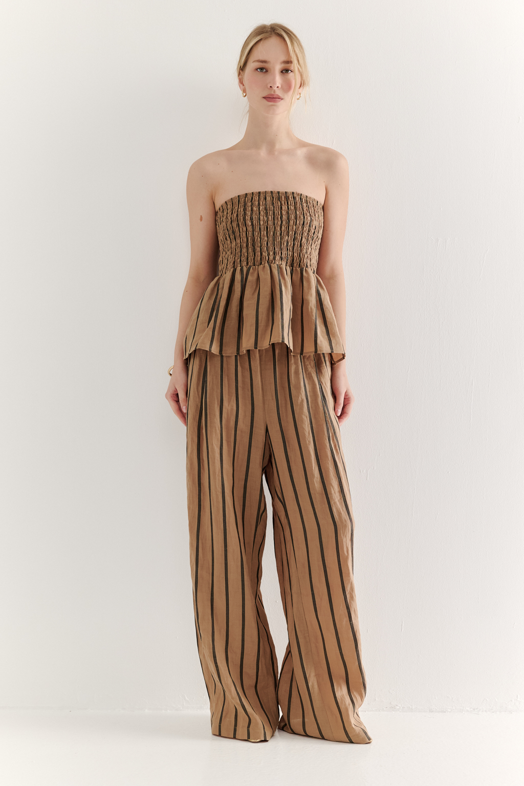 Топ-бандо из эластичных стрейч-нитей, выполненный из платьевой ткани с полской. Состав ткани представляет собой гармоничное сочетание натуральных волокон крапивы и хлопка, обработанных методом растительного окрашивания (natural dye), что обеспечивает экологичность и мягкость материала. Топ состоит из двух основных частей: верхней присборенной бандо-секции и нижней части топа. Поддержка обеспечивается съемными бретелями, которые позволяют варьировать стиль ношения.