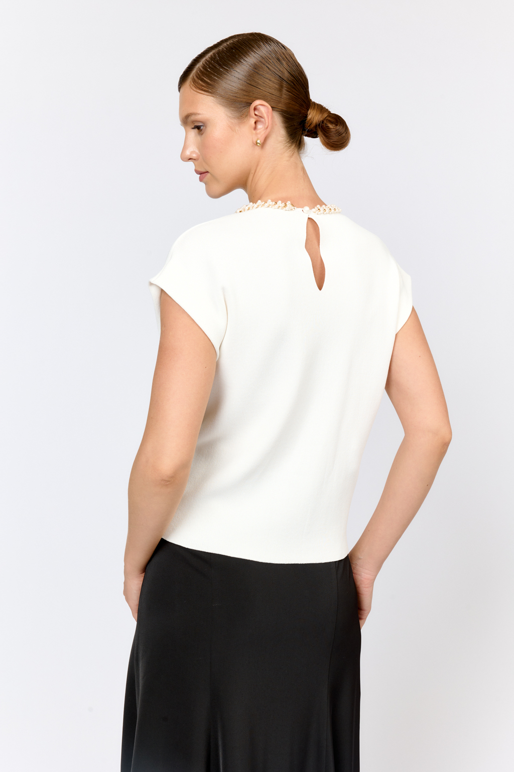 Элегантный топ  с круглой горловиной, декорированной тесьмой. Со спущенным плечом, без рукавов. Свободного силуэта. Изысканная модель из премиального  трикотажа плотной вязки в  молочном цвете. Сбалансированная комбинация вискозы и полиамида  создает комфорт при носке. Материал хорошо держит форму  и не подвержен деформации.  Лаконичный топ с декоративной тесьмой  в молочном оттенке - утонченное решение для вечерних или деловых образов.