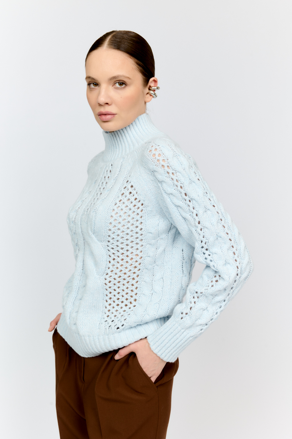 Свитер голубого цвета из мягкой пряжи фигурной вязки с ассиметричными косами, с высокой горловиной и длинным рукавом реглан отлично стилизуется с денимом и обувью на плоском ходу.