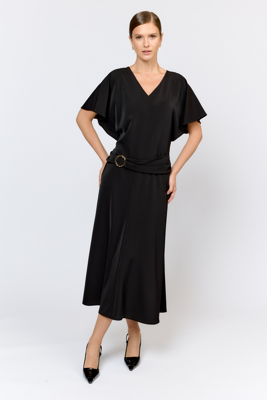 Струящееся платье свободного кроя с цельнокроеными рукавами и открытой горловиной с V-образным вырезом горловины. Модель с декоративной пряжкой на притачном поясе со сборкой по бокам. Выполнено из эластичной плательной ткани. Полиэстер придает ткани устойчивость к сминанию и хорошо держит форму. Что позволяет изделию сохранять опрятный вид в течении дня.  Глубокий черный цвет не тускнеет после стирки. Спандекс добавляет эластичность, обеспечивая идеальную посадку по фигуре. Преимущества ткани: новое современное качество с мягким блеском и благородной фактурой. Ткань легкая, приятна к телу, красиво драпируется при движении. Глубокий черный оттенок придает изделию благородный вид.