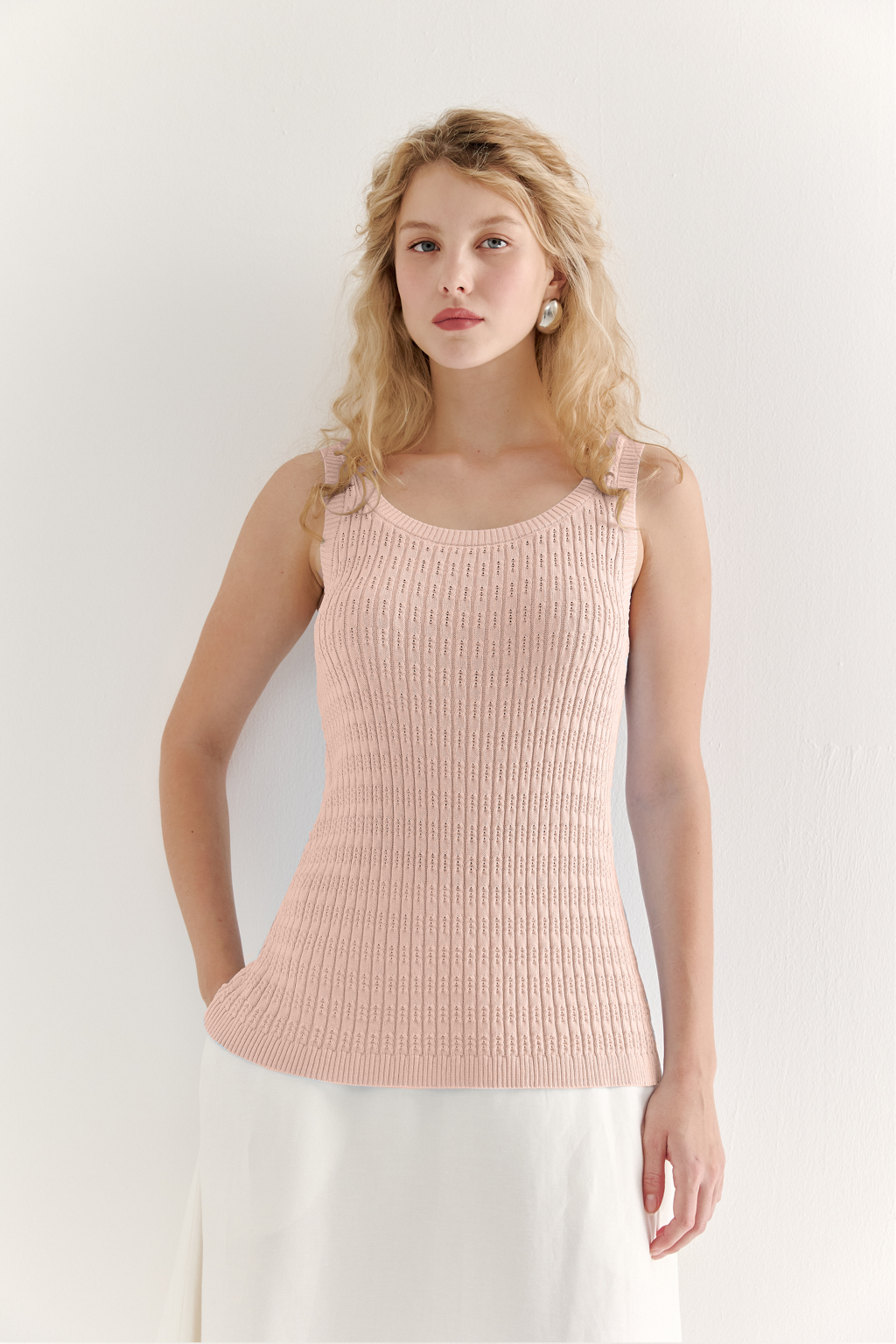 Фактурный топ-майка прилегающего силуэта из вискозной пряжи связана косами, проймы и горловина отделаны вязанными кантами. Цвет – розовая пудра.