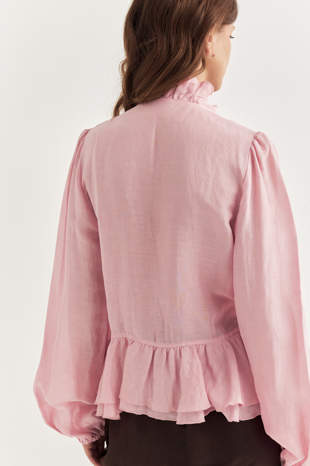Блуза, выполненная в стиле бохо-шик, предстает в нежном розовом оттенке. Ткань, сотканная из льна и вискозы, дарит ощущение легкости. Рюши изящно обрамляют борт и низ изделия, втачной рукав, слегка расширяющийся книзу, завершается мягким объемным манжетом. Блуза завязывается на шнуры-рулики.  Создавайте из этой блузы романтические образы, используйте ее также как второй слой для  многослойного сложного образа.