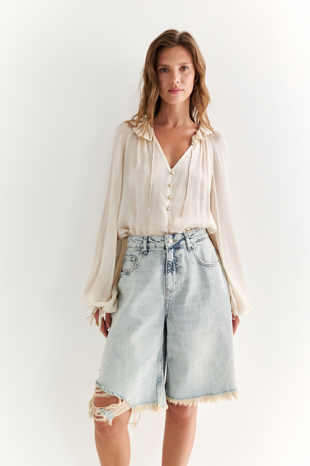 Широкие женские джинсовые шорты ниже колена из легкого денима. Рваные края придают изделию оригинальности.