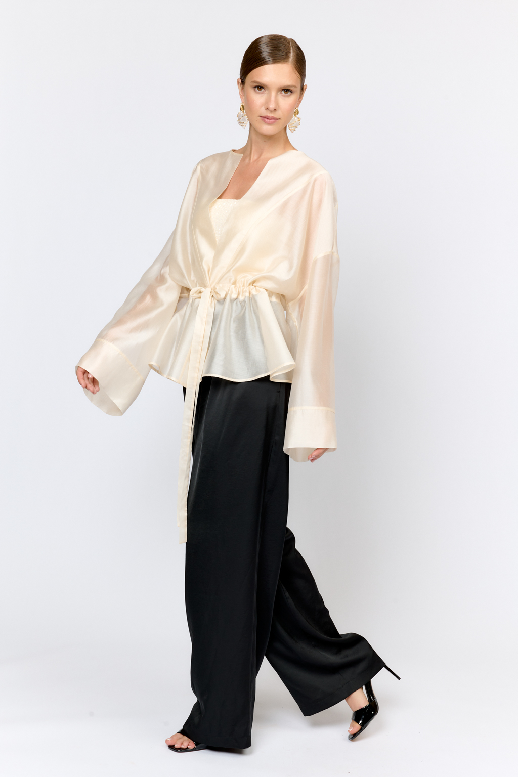 Нарядная блуза из полупрозрачной ткани на кулиске по талии и широкими рукавами большого объема с широкими манжетами по низу дополнит образ с брюками, юбками и платьями в качестве верхнего слоя или в дополнении с топом.  Выполнена из легкой полупрозрачной ткани из тенселя  с содержанием шёлка. Тенсель  -  волокно растительного происхождения, получаемое из древесины эвкалипта по экологически чистому технологическому процессу. Отличается  воздухопроницаемостью и гигроскопичностью.  Шёлк обеспечивает роскошный внешний вид и пластичность ткани.  Преимущества ткани: шелковистая поверхность ткани с жемчужным переливом выглядит премиально и нарядно. Легкая прозрачность делает образ трендовым.