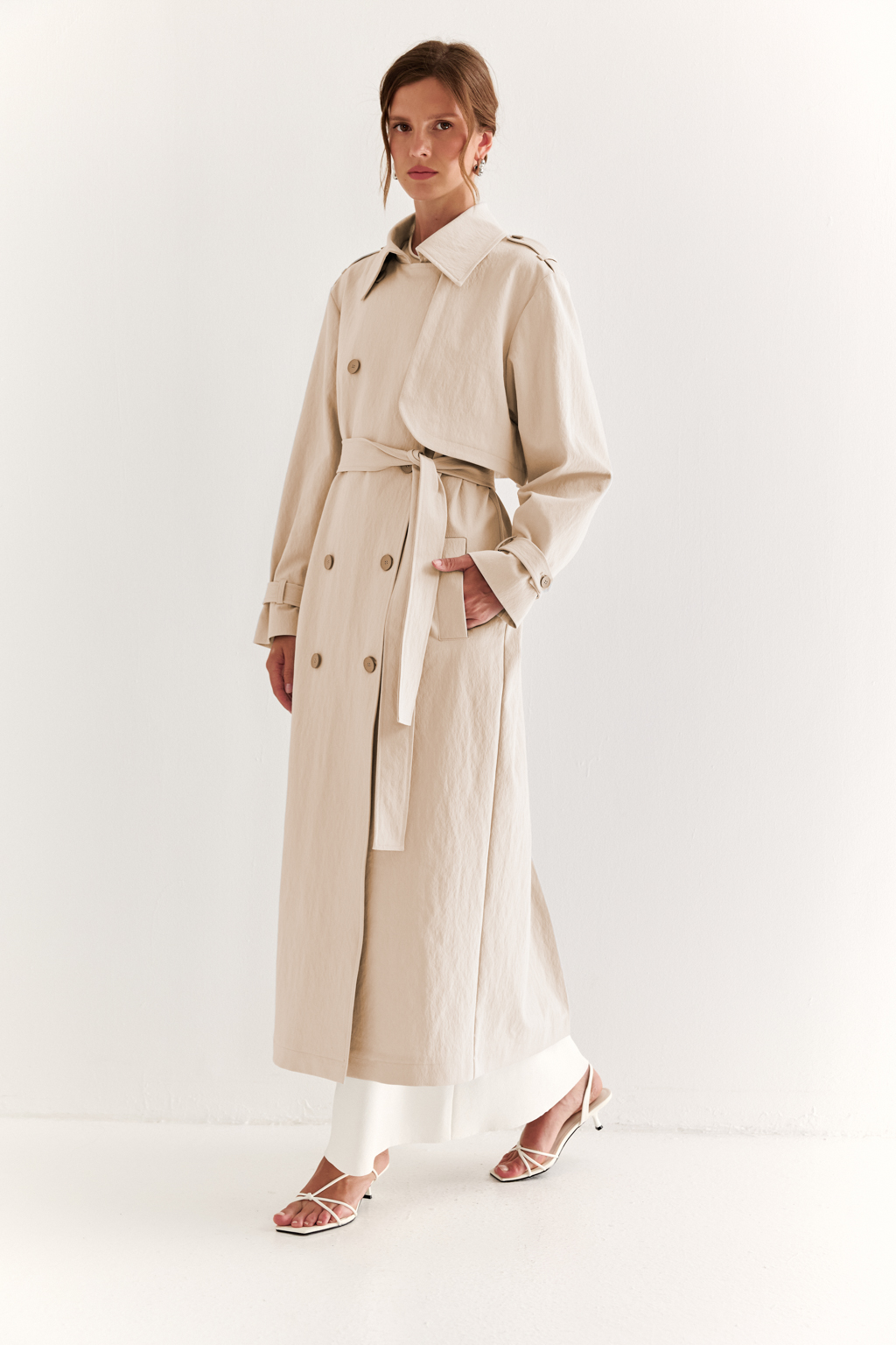 Плащ двубортный прямого силуэта длиной макси с расширенной линией плеча и отлётными кокетками по полочке и спинке. Приталивается завязывающимся поясом.