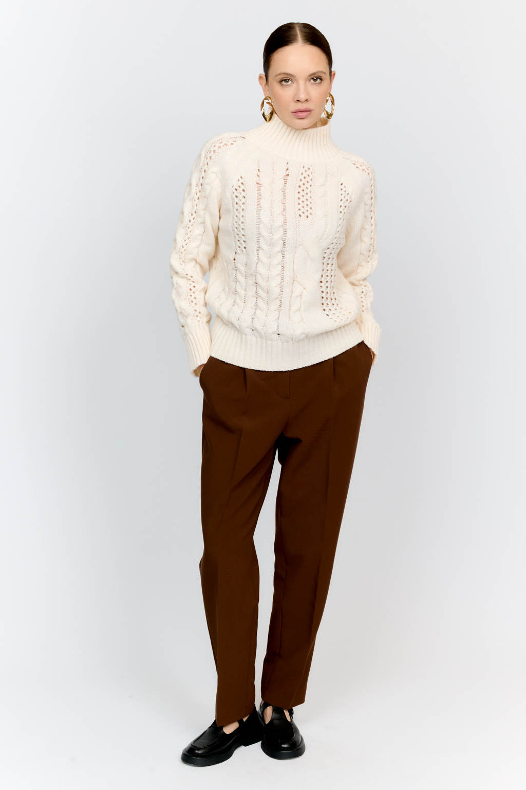 Свитер молочного цвета из мягкой пряжи фигурной вязки с ассиметричными косами, с высокой горловиной и длинным рукавом реглан отлично стилизуется с денимом и обувью на плоском ходу.