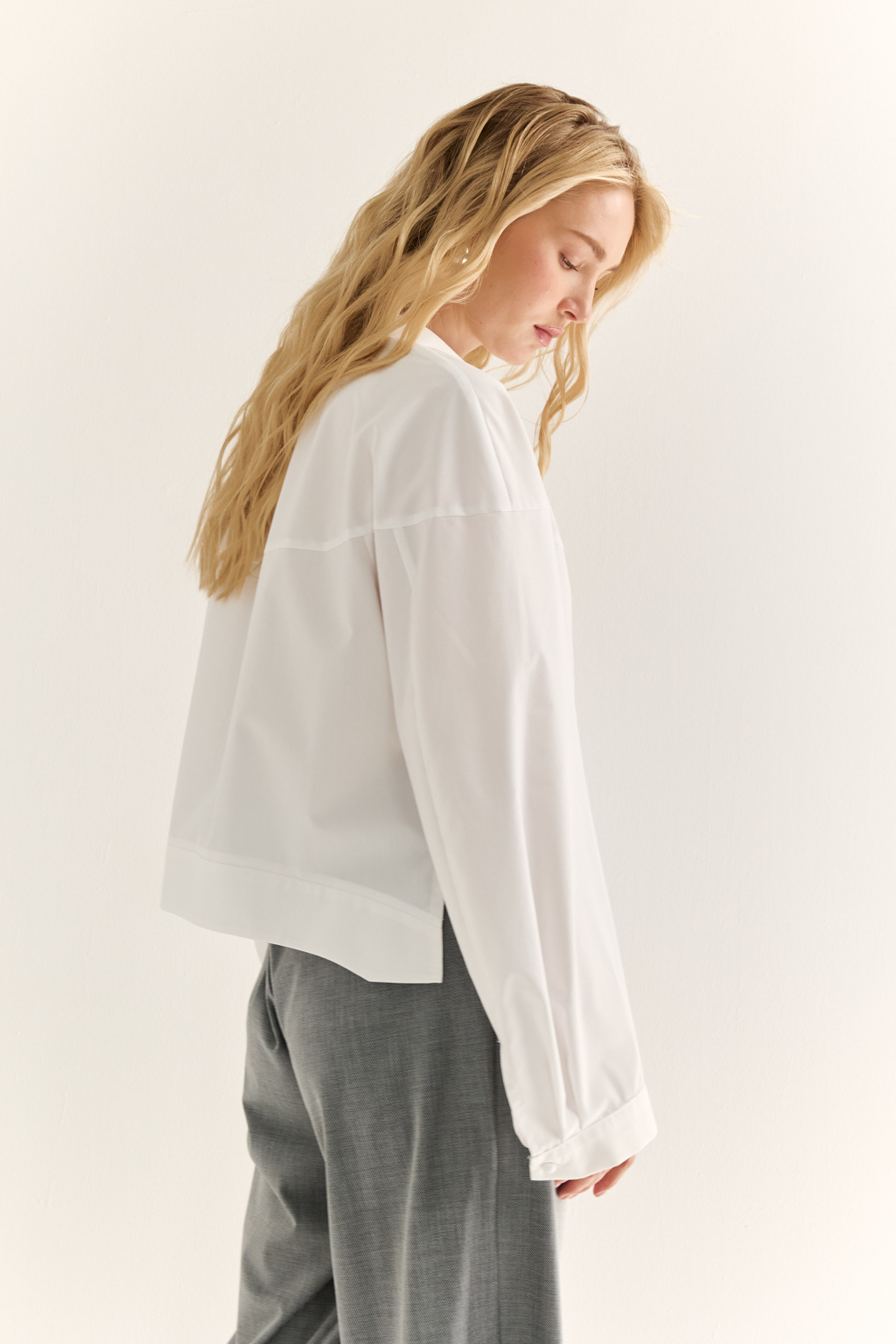 Oversize-рубашка с кокеткой: объём как способ выразить себя. Эта укороченная рубашка с удлинённой кокеткой и объёмными рукавами — модный акцент, который задаёт ритм всему образу. Мягко закруглённый низ подчёркивает талию и визуально вытягивает силуэт, а объёмный крой создаёт эффект расслабленного шика. Широкая кокетка, фактурные швы и сборка по рукавам добавляют архитектурности и свежести классической рубашке. Застёжка на пуговицы и аккуратный воротник сохраняют баланс между формальностью и актуальностью. Новая форма свободы — уверенная, воздушная, выразительная.