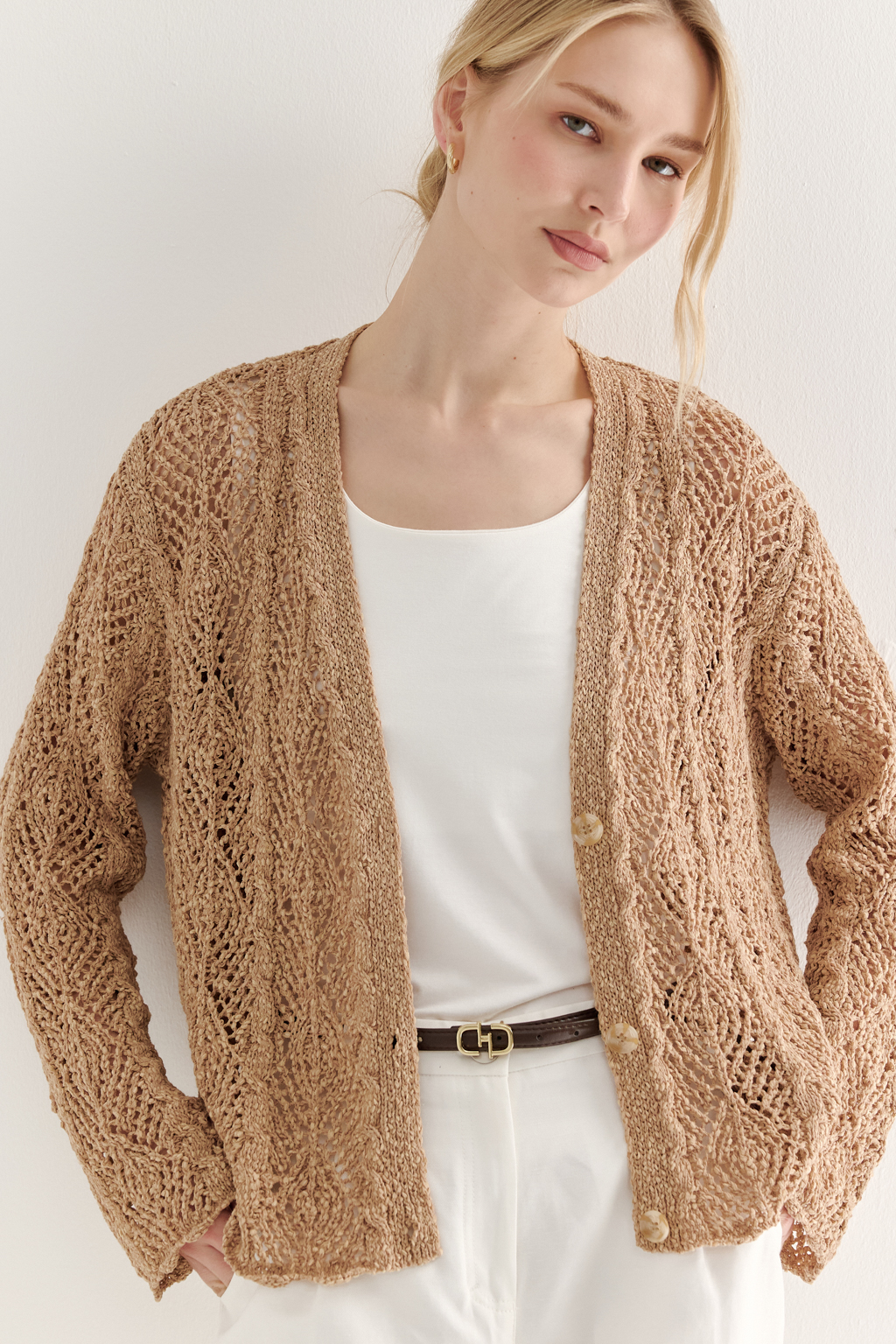 Бежевый вязаный кардиган оверсайз силуэта из хлопковой пряжи. Кардиган связан в сложной технике комбинирования сетки и ажурных ромбов. Рукав прямой удлиненный, V-образный вырез, борт отделан планкой, застежка по борту на 3 пуговицы, низ кардигана и рукав – сложные фестоны.