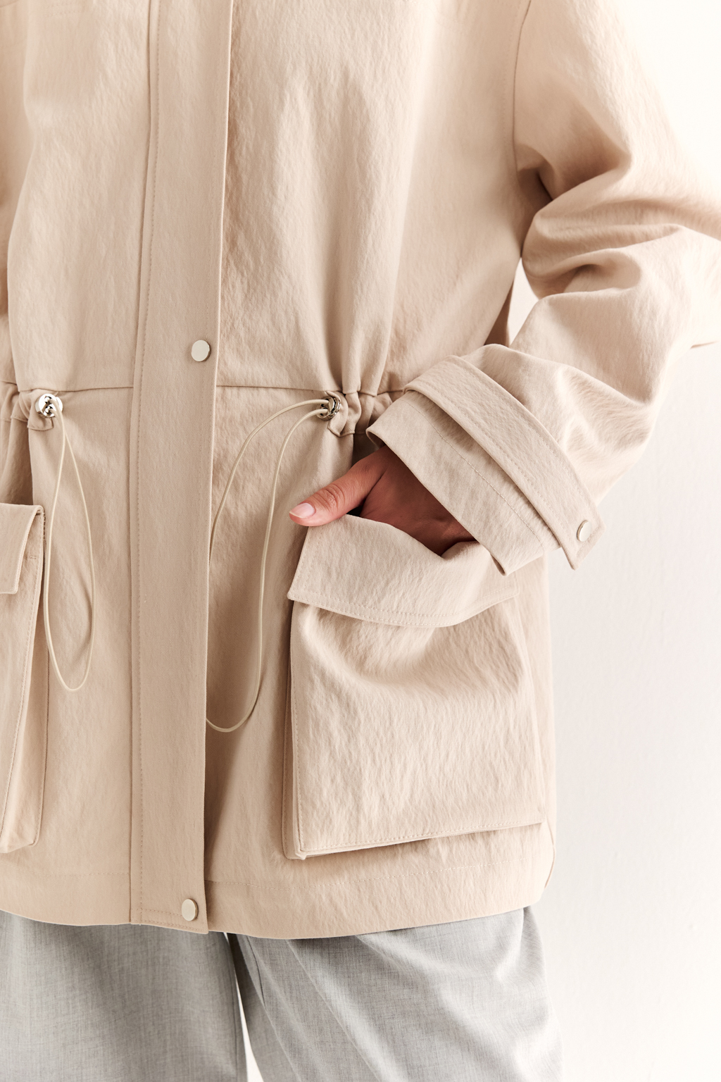 Куртка прямого силуэта длиной до бедер и с кулисой по талии. Воротник рубашечный, застежка под планкой. По полочке накладные карманы-портфели.