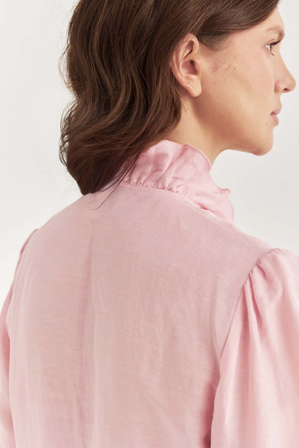 Блуза, выполненная в стиле бохо-шик, предстает в нежном розовом оттенке. Ткань, сотканная из льна и вискозы, дарит ощущение легкости. Рюши изящно обрамляют борт и низ изделия, втачной рукав, слегка расширяющийся книзу, завершается мягким объемным манжетом. Блуза завязывается на шнуры-рулики.  Создавайте из этой блузы романтические образы, используйте ее также как второй слой для  многослойного сложного образа.