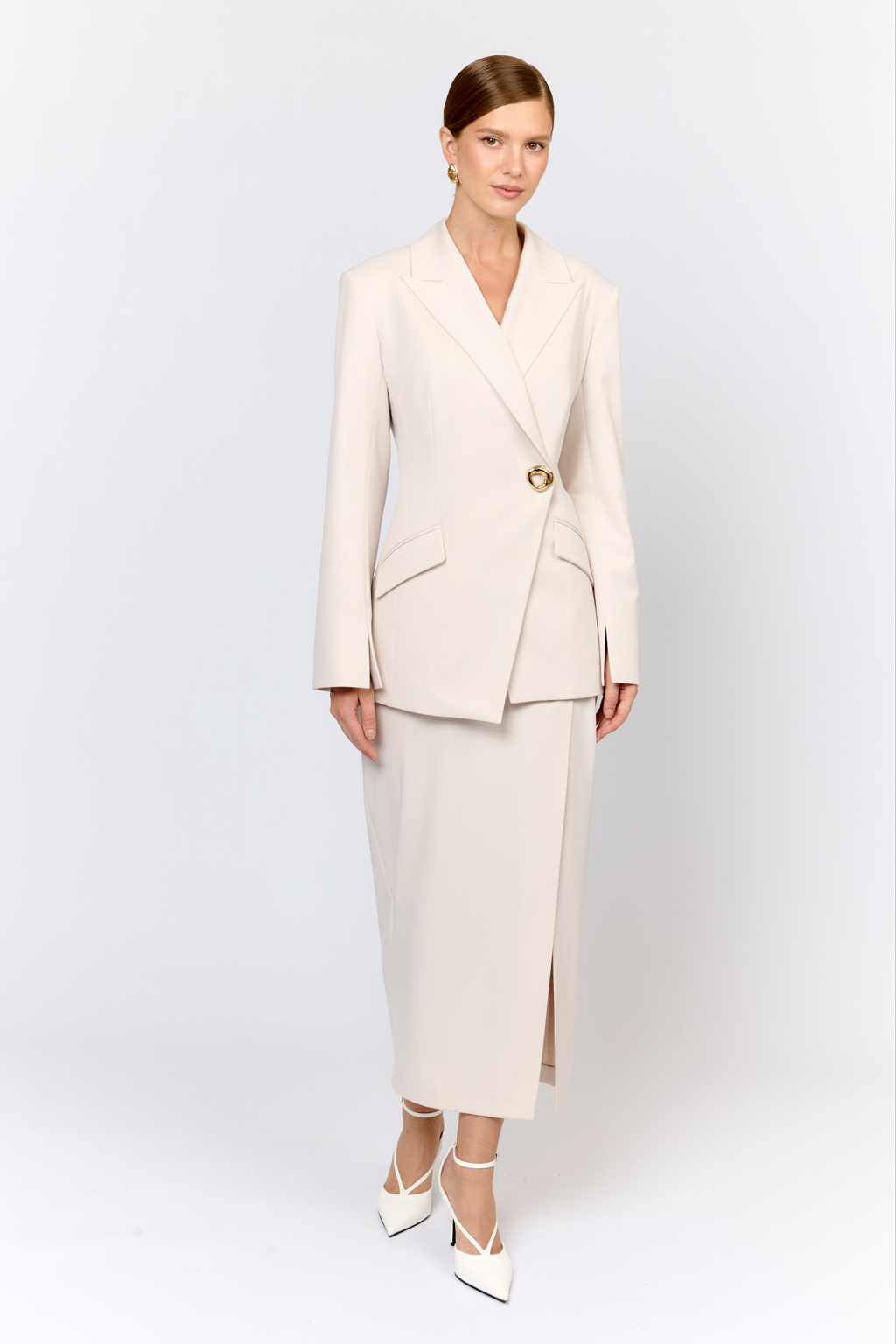 Приталенный жакет с асимметричным бортом по низу и расклешенными рукавами с разрезами - трендовая модель, которую легко вписать как в праздничный, так и в повседневный образ. Модель выполнена из костюмной ткани с содержанием шерсти и шелка. Шерсть в составе придает тепло, мягкость и благородную фактуру. Шёлк отвечает за легкий благородный блеск. Полиэстер обеспечивает легкость в уходе и несминаемость.   Полуприлегающий крой жакета, с акцентом на талию, английский воротник и четкая линия плеч формируют изящный, элегантный силуэт. Преимущества ткани: сочетание шерсти и шёлка создает премиальный эффект и уникальные тактильное ощущения. Материал держит форму, устойчив к износу. Гладкая поверхность выглядит дорого и изысканно. Приятный жемчужный цвет придает образу праздничный вид.