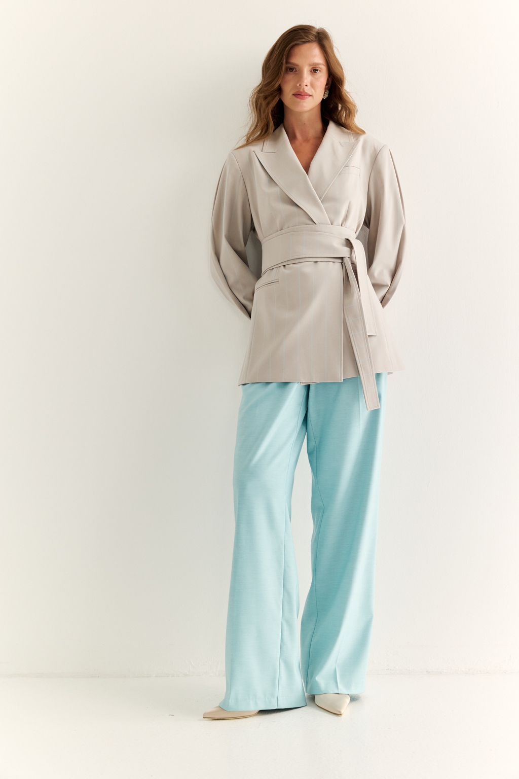 Жакет с поясом-кушаком: мягкая сила и подчёркнутая линия. Этот жакет сочетает в себе структурированную форму и пластичность драпировки. Приталенный силуэт акцентирован широким поясом-кушаком, который завязывается на талии, формируя выразительную линию «песочных часов» и добавляя образу женственности без излишней строгости.
Острые лацканы, аккуратная линия плеч и выверенный крой рукавов делают модель универсальной: для делового дня, кэжуал-комплекта или вечернего выхода. Пояс, завязанный на узел или бант, задаёт настроение и подчеркивает индивидуальность. Гармония формы и мягкости. Жакет, который раскрывает силу через утончённость.