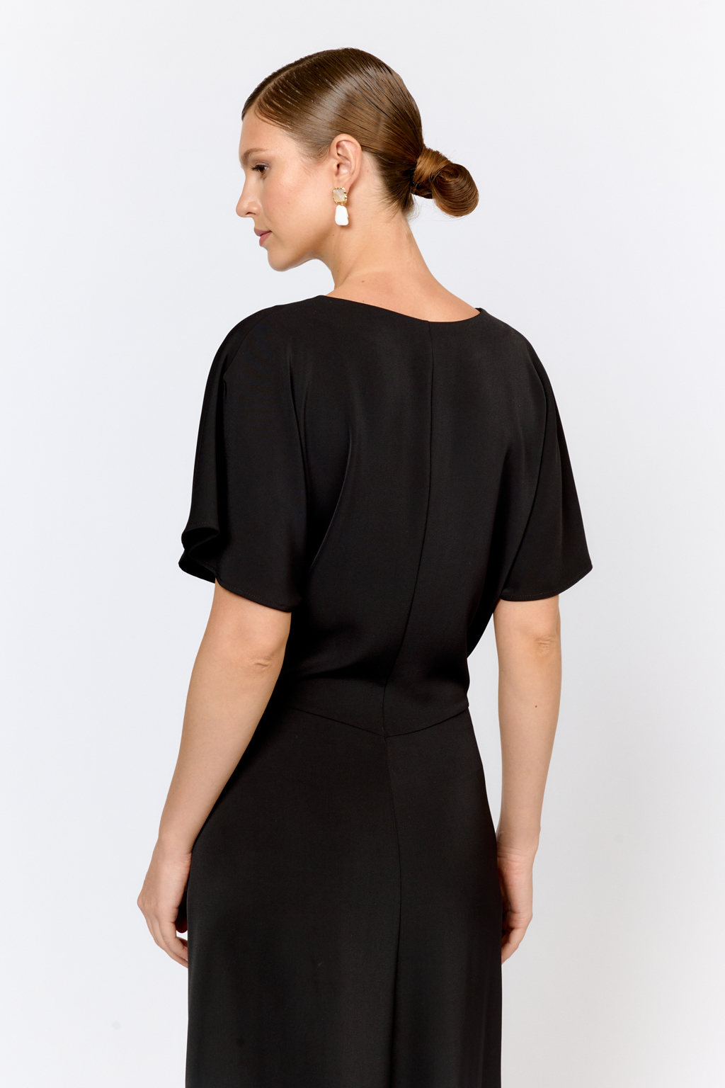 Струящееся платье свободного кроя с цельнокроеными рукавами и открытой горловиной с V-образным вырезом горловины. Модель с декоративной пряжкой на притачном поясе со сборкой по бокам. Выполнено из эластичной плательной ткани. Полиэстер придает ткани устойчивость к сминанию и хорошо держит форму. Что позволяет изделию сохранять опрятный вид в течении дня.  Глубокий черный цвет не тускнеет после стирки. Спандекс добавляет эластичность, обеспечивая идеальную посадку по фигуре. Преимущества ткани: новое современное качество с мягким блеском и благородной фактурой. Ткань легкая, приятна к телу, красиво драпируется при движении. Глубокий черный оттенок придает изделию благородный вид.