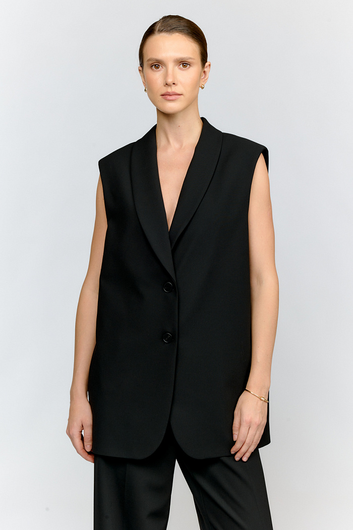 Стильный жилет в оверсайз-силуэте из благородной костюмной ткани черного цвета. Зауженный книзу крой и воротник-шалька делают модель универсальной для многослойных образов. Прекрасно встроится в расслабленные образы с широкими джинсами и кедами на плоском ходу.
