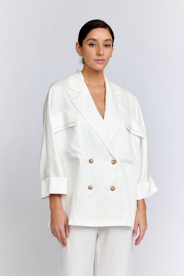 Жакет двубортный оверсайз силуэта с разрезами по бокам, и цельнокроенными рукавами, длиной 7/8. Английский воротник. По полочке два накладных кармана с двойными клапанами.