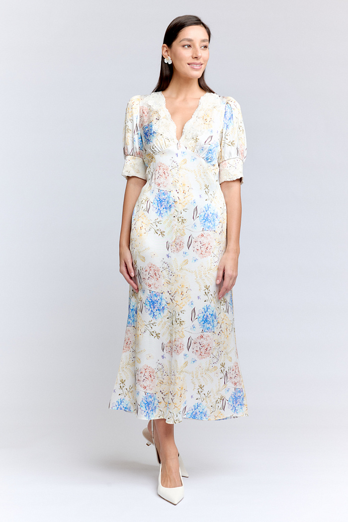 Женственное платье приталенного силуэта с глубоким v-образным вырезом горловины, отделанным кружевом, струящееся по низу, благодаря крою юбки-годе. Выполнено из атласной вискозы.