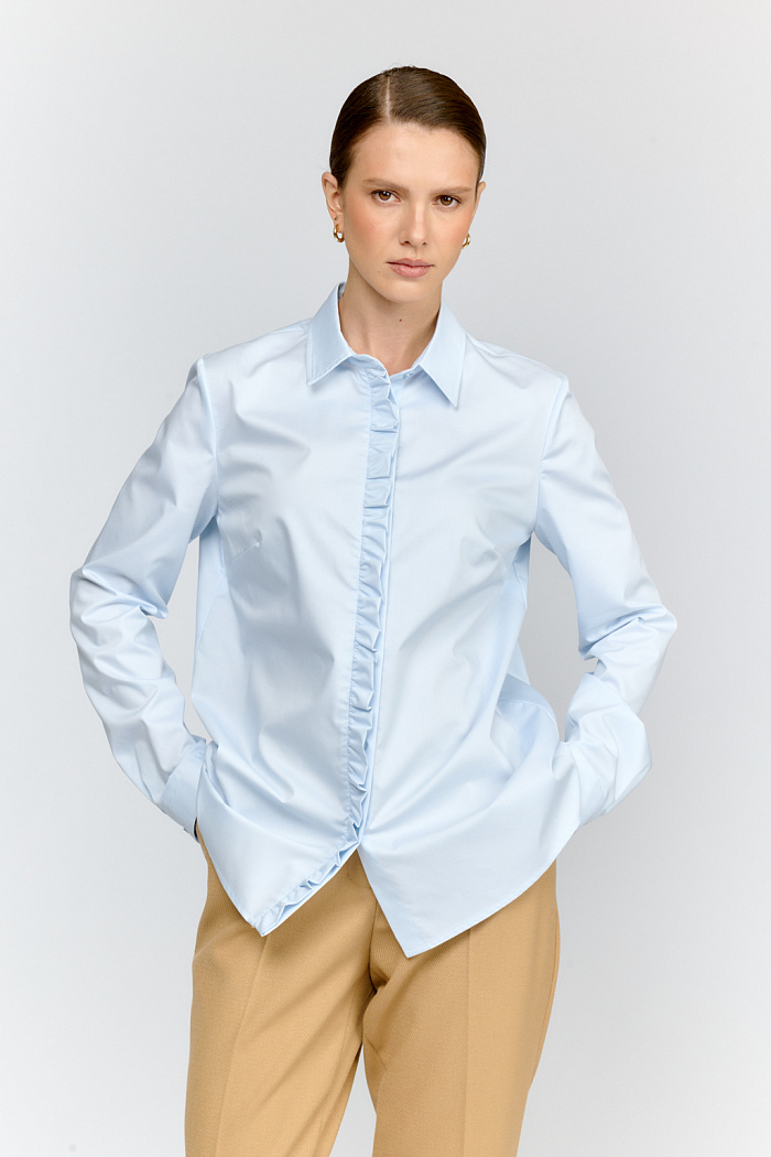 Рубашка из смесового хлопка в небесно голубом цвете с  декоративной рюшей по центру. Классический прямой силуэт и застёжка на пуговицы делают модель универсальной базой для любого образа.