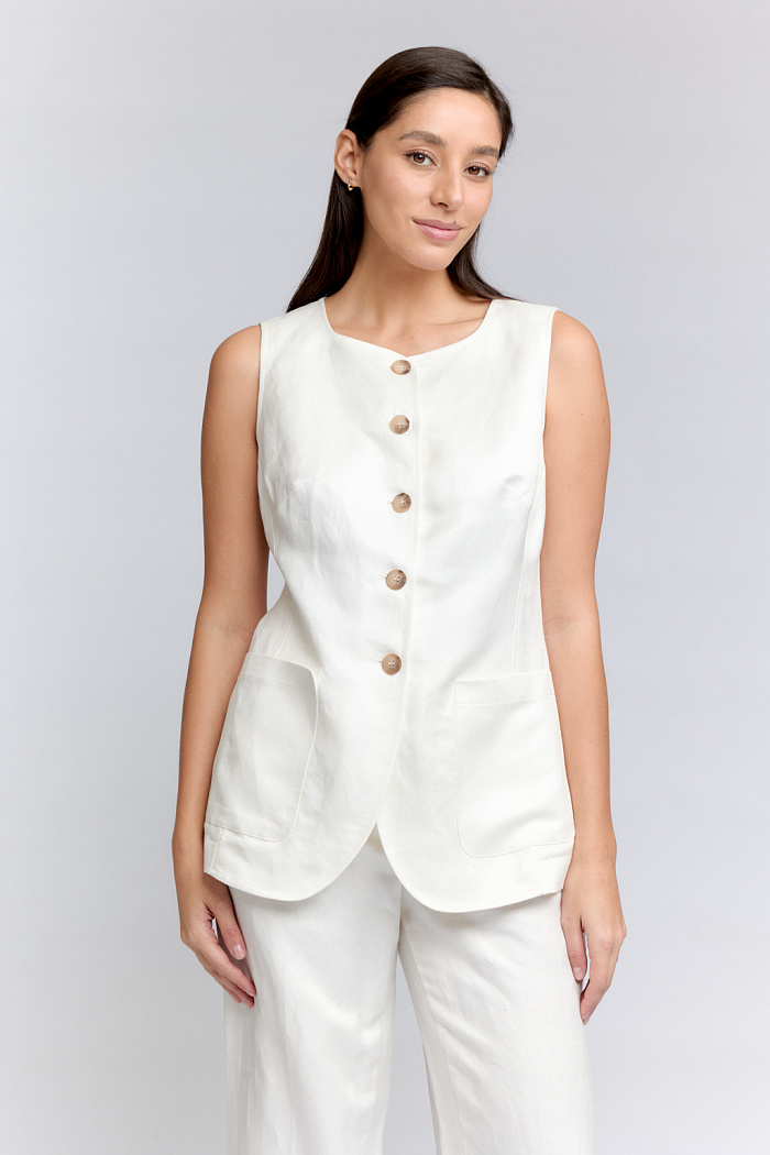 Жилет приталенного силуэта с двумя накладными карманами и закругленными бортами. Длина до середины бедер.