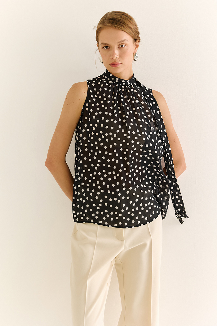 Блузка с бантом: женственность и утончённый акцент. Эта блузка без рукавов — воплощение элегантной простоты с выразительной деталью. Горловина украшена мягким бантом, который добавляет образу нотки утончённости и романтичного шика. Лёгкая драпировка спереди делает силуэт свободным, но изящным, подчёркивая вкус и стиль. Идеальна для офисных будней, деловых встреч или вечерних образов. Эффектно смотрится под жакет или кардиган, но и сама по себе становится акцентом. Сила — в деталях. Женственность — в каждом движении.
