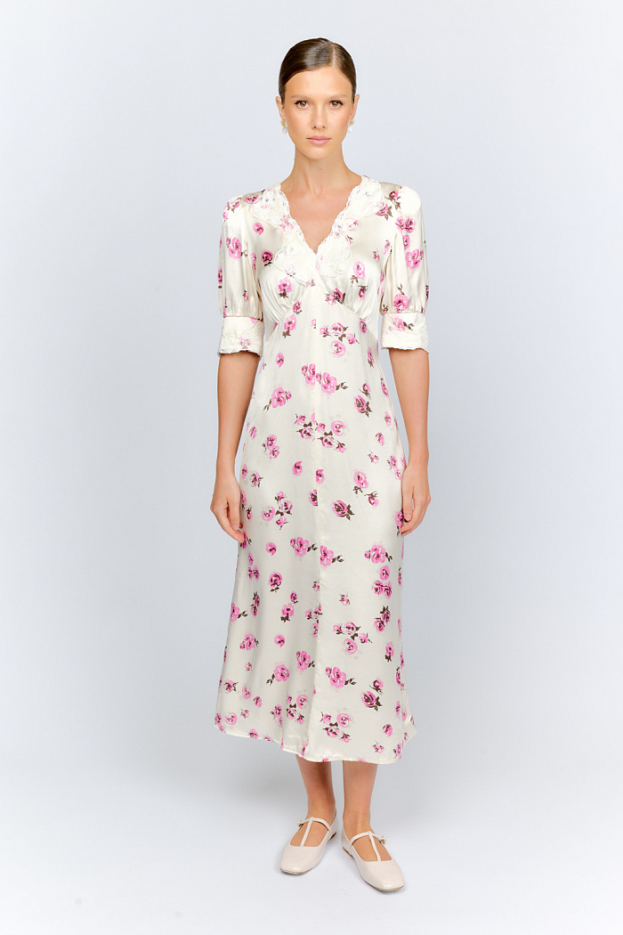 Женственное платье приталенного силуэта с глубоким v-образным вырезом горловины, отделанным кружевом, струящееся по низу, благодаря крою юбки-годе. Выполнено из атласной вискозы.