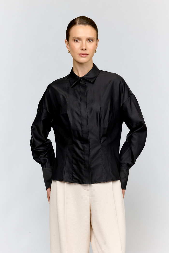 Укороченная рубашка со спущенными плечами изткани черного цвета — стильная вещь для создания  разных образов. Складки по полочке структурируют силуэт, выгодно подчеркавая талию, а спущенное плечо создаёт современный силуэт. Сочетайте с джинсами и брюками, юбками различных фасонов, лоферами или балетками, сумкой через плечо.