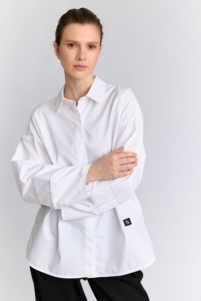 Блуза оверсайз силуэта с декоративными манжетами и контрастной строчкой.