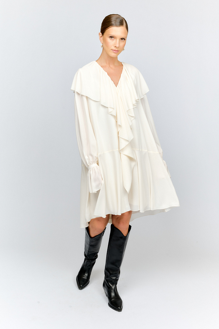 Платье в бохо-стиле из легкого шифона с глянцевым напылением, создающим эффект кожи свободного расклешенного силуэта. По вороту широкие воланы переходят в струящиеся линии спереди почти до самого низа платья. Рукава обьемные на манжетах с застежками и длинными рюшами. Платье состоит из двух элементов: само платье и комбинация в качестве подкладки.