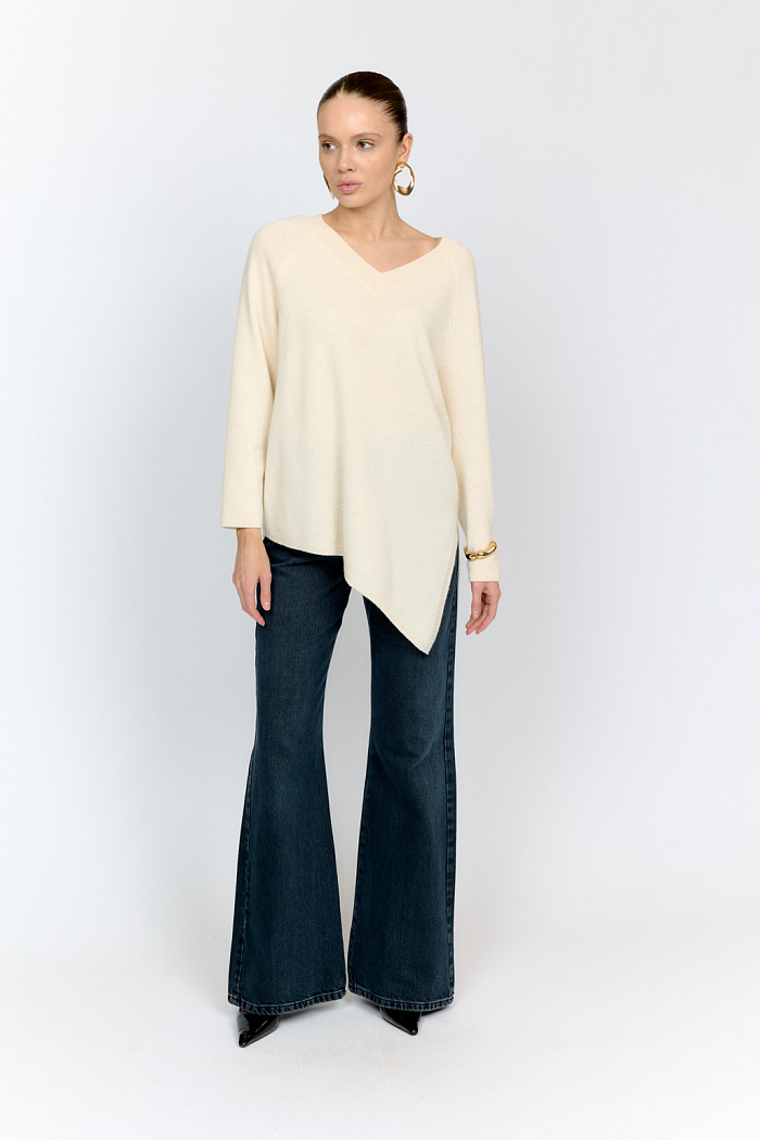 Однотонный джемпер из 100% экстрафайн шерсти в молочном цвете с V-образной горловиной, рукавом реглан и асимметричным низом с боковым разрезом - must have для создания стильных образов на холодную осень.