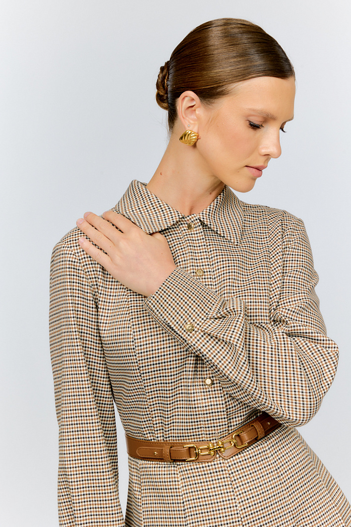 Платье приталенного силуэта с отложным воротником и застежкой на пуговицы спереди из костюмной ткани с содержанием вискозы в клетку на молочном фоне с крупными складками по юбке создает женственный теплый осенний образ. Платье идеально сочетается с ремнем из кожи карамельного цвета с золотой фурнитурой, который предлагается также в коллекции.