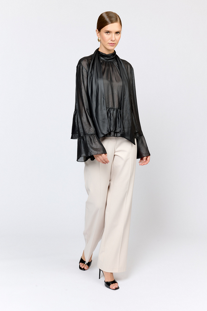 Блуза свободного кроя с летим расширением книзу с воланами по низу и воротником-стойкой, переходящим в ленты, которые можно завязать в бант либо просто перекинуть через плечи. Выполнена из легкой полупрозрачной ткани с глянцевым напылением, создающим эффект кожи. Полиэстер легкий и воздушный материал, создающий ощущение невесомости, практичен в уходе,  устойчив к сминанию. Преимущества ткани: высокотехнологичный материал премиального качества с оригинальным напылением, имитирующим кожу. Ткань пластично драпируется и красиво движется. Приглушенный блеск придает образу нарядность, а необычная фактура делает его стильным.