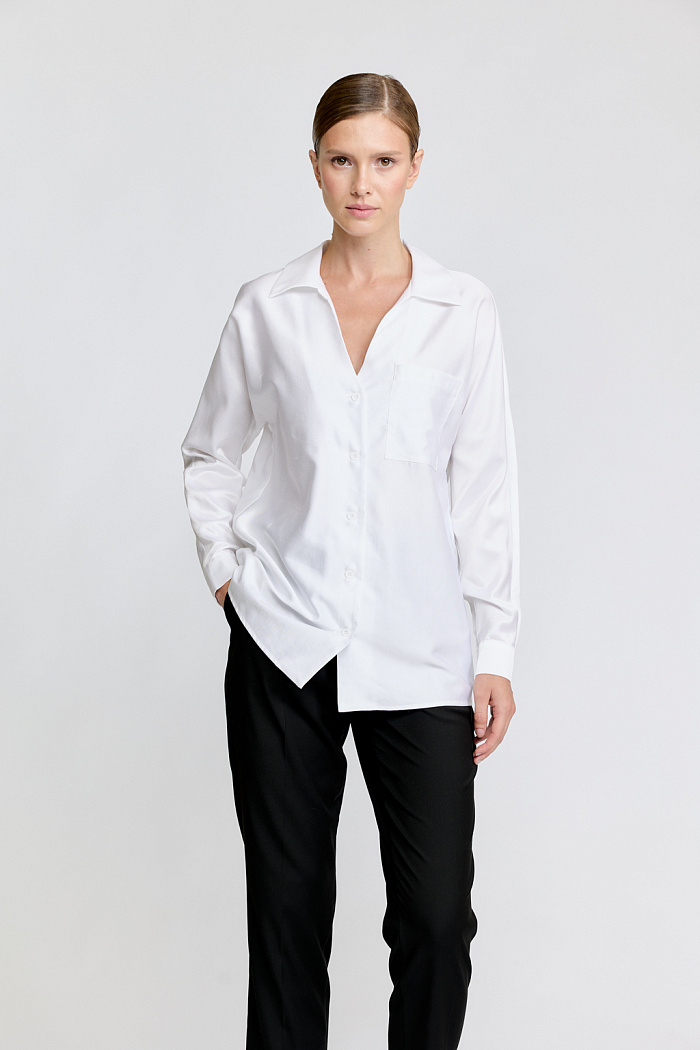 Блуза прямого силуэта с V-образным вырезом и рубашечным  воротником. По полочке расположен один накладной карман.