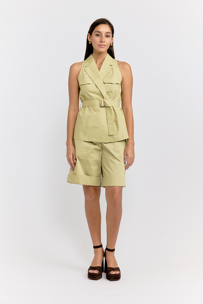 Жилет приталенного силуэта с английском воротником с двумя клапанами спереди. Застежка на две пуговицы, пояс с пряжкой.