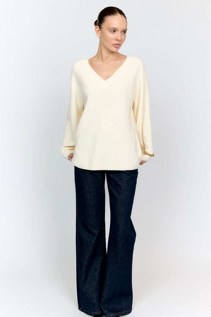Трикотажный джемпер молочного цвета свободного силуэта с V-образным вырезом горловины и рукавами реглан из шерстяной смесовой пряжи станет центром комфортных осенних образов.