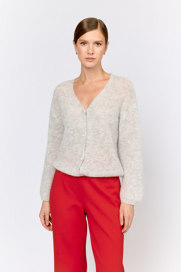 Кардиган с центральной застежкой на пуговицы, V-образной горловиной и длинным рукавом.  Модель свободного силуэта в жемчужно-сером  оттенке из воздушной пряжи с шерстью и мохером с деликатными мелкими пайетками, придающими легкое сияние. Кардиган очень теплый, несмотря но свою трендовую транспарентность и легкость, благодаря мохеру в составе. Шерсть так же обеспечивает естественную терморегуляцию и уют. Такой кардиган будет выигрышно смотреться в образах с  брюками и юбками из коллекции, а так же дополнит образы с платьями на бретелях или платьем-бандо.