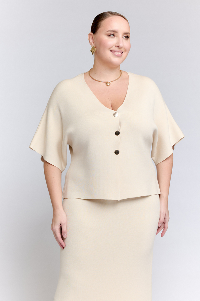 Кардиган с V-образным вырезом горловины и с цельнокроеными рукавами.  Застежка на три декоративных пуговицы.