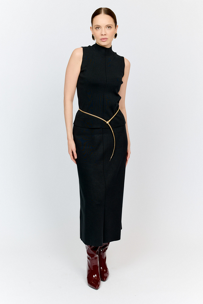 Юбка черного цвета силуэта трапеция длиной миди с завышенной талией подчеркивает природную женственность фигуры. Фасон с расклешением к низу визуально стройнит бедра и корректирует фигуру, зрительно удлиняет ноги. Хорошо сочетать с приталенными джемперами и топами из аналогичной пряжи.