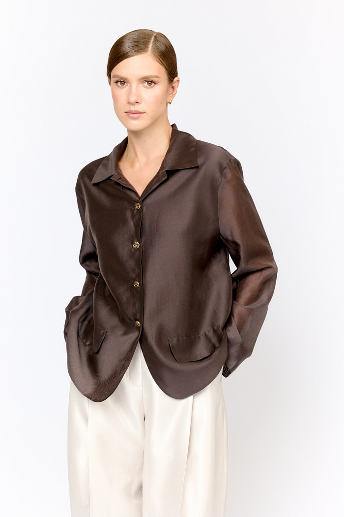 Блуза-жакет среднего объёма с отложным воротником и застежкой на пуговицы. Спереди декоративные клапаны, имитирующими карманы жакета. Спереди изделие двухслойное, сзади - в один слой ткани с легкой прозрачностью.  Выполнена из легкой полупрозрачной ткани из тенселя  с содержанием шёлка. Тенсель  -  волокно растительного происхождения, получаемое из древесины эвкалипта по экологически чистому технологическому процессу. Отличается  воздухопроницаемостью и гигроскопичностью.  Шёлк обеспечивает роскошный внешний вид и пластичность ткани.  Преимущества ткани: шелковистая поверхность ткани с жемчужным переливом выглядит премиальное и нарядно. Легкая прозрачность делает образ трендовым.  Необычное решение облегченного жакета  в трендовом  цвете  "Dark ocean" поможет создать уникальный модный образ для праздничного вечера.