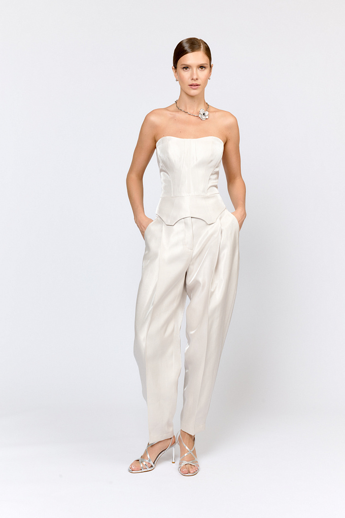 Корсет с баской с фигурной линией по низу, на косточках по рельефам. Выполнен из района  в жемчужно-сером цвете. Новое качество с  легким блеском и неявной диагональной фактурой. Район в составе ткани отвечает за мягкость и пластичность, приятные тактильные ощущения. Нейлон хорошо держит форму и устойчив к истиранию. Так же нити нейлона придают блеск, имитирующий натуральный шёлк. Корсет может дополнить образ как в качестве предмета первого слоя, так и  поверх хлопковой блузы или  лонгслива. Тотал лук с брюками  подойдет для смелых стильных образов.  Корсет можно комбинировать с классическим костюмом, в качестве первого слоя, для создания более сдержанного повседневного образа.