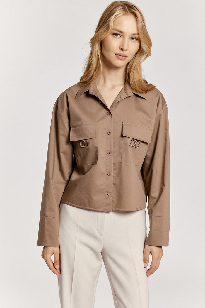 Блуза длиной до талии с накладными карманами и декоративной вышивкой.